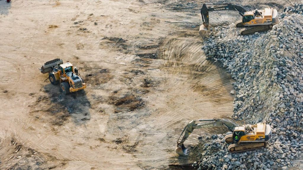 Three yellow excavators near front end loader